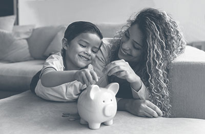 Saving for the Future, mom and child putting coins into piggy bank.