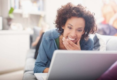 Woman laying on couch on laptop.