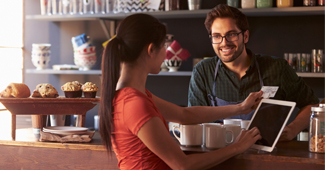 Woman swiping card on tablet to pay in cafe.